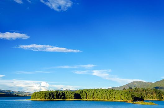 Beautiful blue lake with a wooded island and green hills in Neusa, Colombia