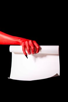 Red devil hand with black nails holding paper scroll, deal with devil concept 