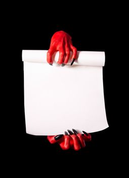 Red devil hands holding paper scroll, deal with devil concept, isolated on black background 