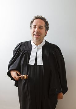 Man in canadian laywer robe tapping a gavel on his belly with a dumb face expression