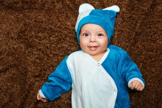 Blue-eyed baby lies on his back and smiling while looking at the camera