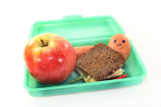 a lunch box with a busy slice of bread and a carrot and an apple