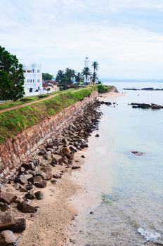 Sea shore with high wall and white lighthouse, Galle fortress, Sri Lanka