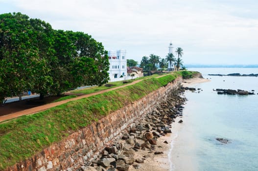 Sea shore with high wall and white lighthouse, Galle fortress, Sri Lanka