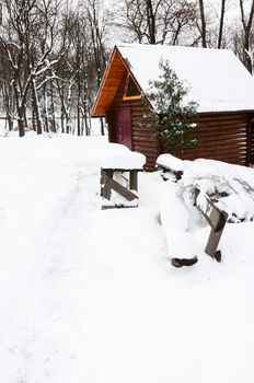 Wooden house and bench after snowfall in winter park