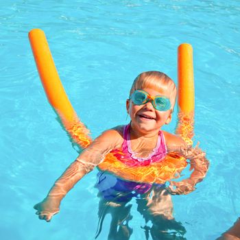Little girl wearing swimming goggles in a hotel pool