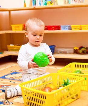 Little baby girl playing with toys at nursery