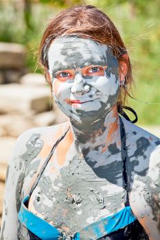 Happy young woman covered with mud