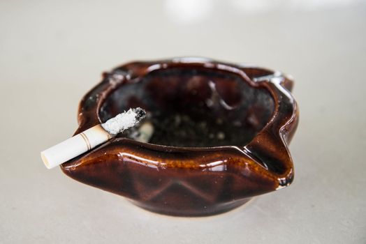 Cigarette resting on an ashtray on the table.