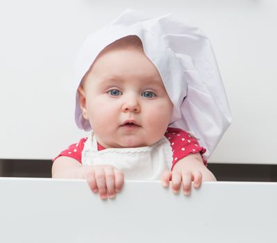 little baby in a chef's hat in the kitchen