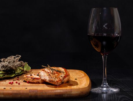 Grilled steak with glass red wine on dark background