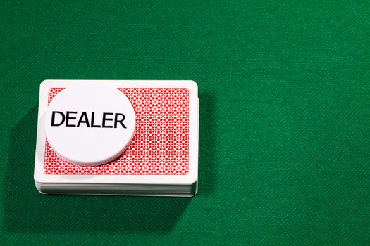 Poker cards with dealer chip on green cloth