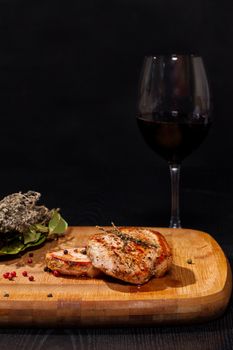 Grilled steak with glass red wine on dark background