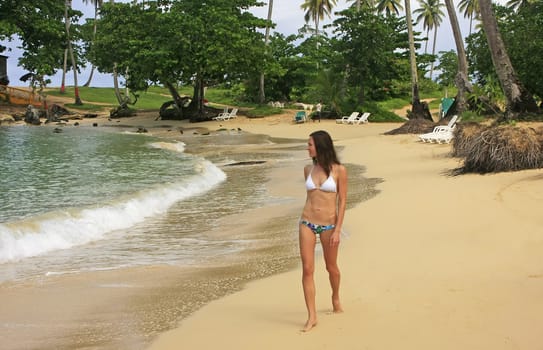 Young woman in bikini walking at Rincon beach, Samana peninsula, Dominican Republic