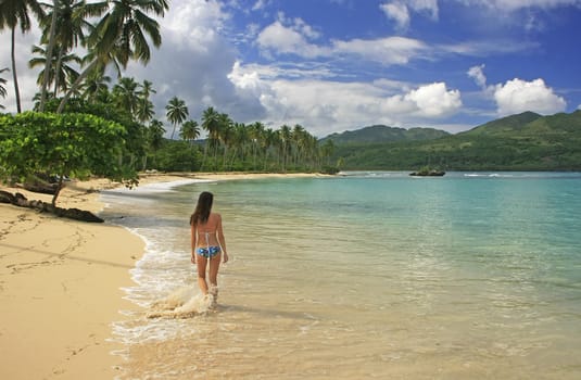 Young woman in bikini walking at Rincon beach, Samana peninsula, Dominican Republic