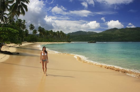 Young woman in bikini walking at Rincon beach, Samana peninsula, Dominican Republic