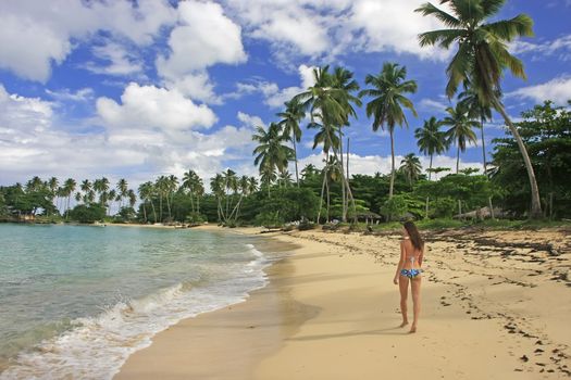 Young woman in bikini walking at Rincon beach, Samana peninsula, Dominican Republic