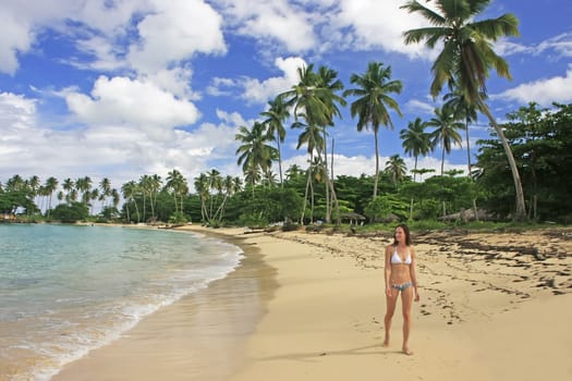 Young woman in bikini walking at Rincon beach, Samana peninsula, Dominican Republic