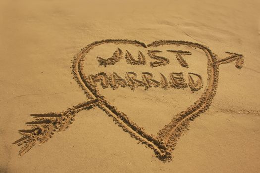 "Just married" written in sand on a beach