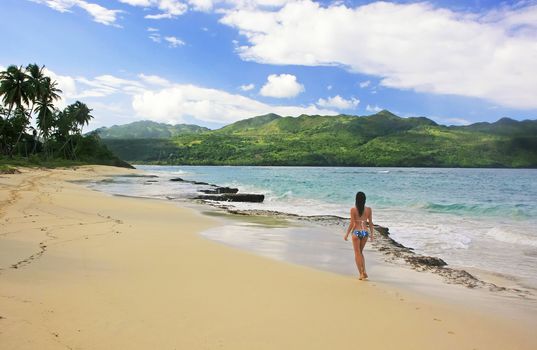 Young woman in bikini walking at Rincon beach, Samana peninsula, Dominican Republic