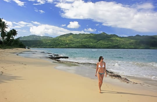 Young woman in bikini walking at Rincon beach, Samana peninsula, Dominican Republic