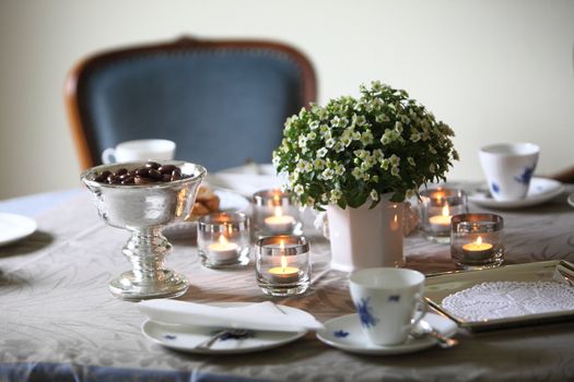 Table setting for a formal tea party with candles and a floral centrepiece