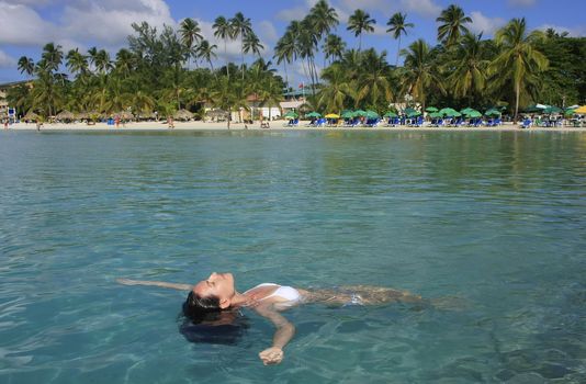 Young woman in bikini floating in clear water, Boca Chica beach, Dominican Republic
