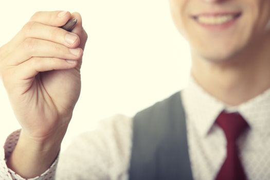 Young smiling businessman is writing on a virtual whiteboard. Focus is on the hand and pen