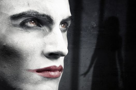 Face of vampire on a dark grungy background with woman shadow