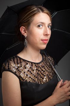 Attractive caucasion girl wearing an evening gown in her 30s shot in studio isolated on a grey background