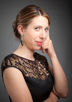 Attractive caucasion girl wearing an evening gown in her 30s shot in studio isolated on a grey background