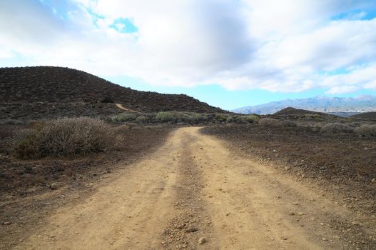 Sand and Rocks Road in the Desert on a Cloudy Sky