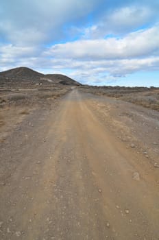 Sand and Rocks Road in the Desert on a Cloudy Sky