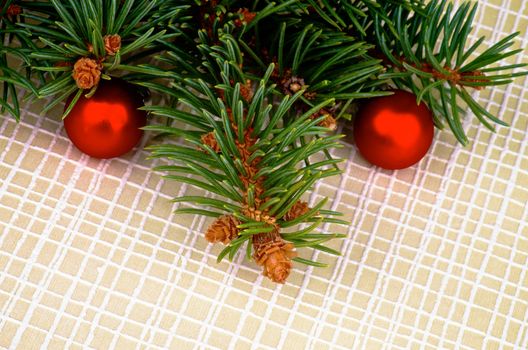 Arrangement of Green Spruce Branch with Fir Cones and Little Red Baubles isolated on Checkered background