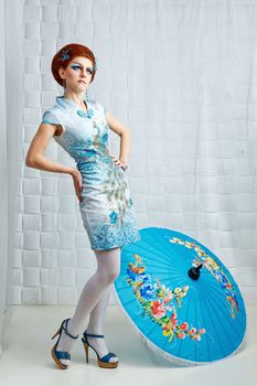 Attractive geisha in a smart dress with an umbrella, photographed in the studio