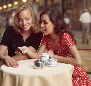 two happy businesswomen with mobile phone in the city