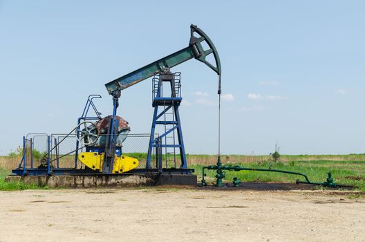 Oil Well Machine in Field on Clear Sunny Day, horizontal shot