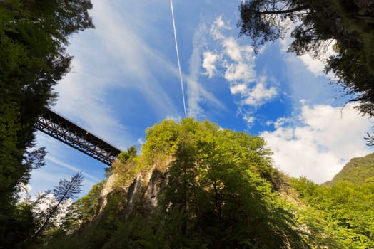 The canyon Slizza (Italy) between a dense forest with blue sky and clouds