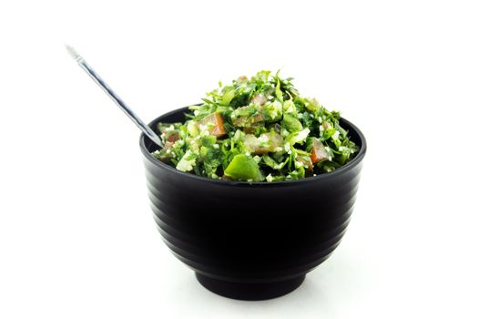 Tabbouleh salad in black plate on white .