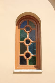 interesting window with colored glass on the background of a pink wall