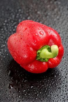 Red bell pepper on black table after rain