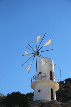 traditional Greek windmill against the blue sky and mountains
