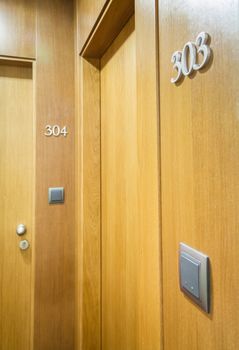 Closeup of wooden door with electronic key and room number in hotel