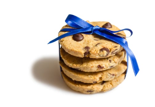 Closeup of homemade chocolate chip cookies tied with blue ribbon, isolated on white background