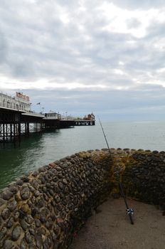 Signal fishing rod resting against a harbour wall with Brighton pier in the foreground.