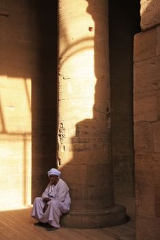 Egyptian man sitting by the column, Philae Temple, Lake Nasser, Egypt