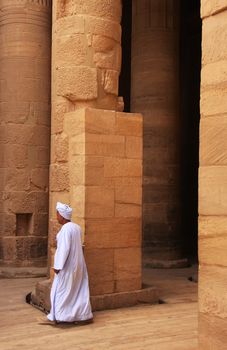 Egyptian man walking by the column, Philae Temple, Lake Nasser, Egypt