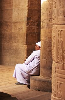 Egyptian man sitting by the column, Philae Temple, Lake Nasser, Egypt