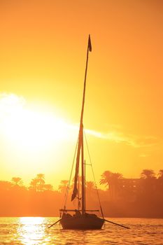 Felucca boat sailing on the Nile river at sunset, Luxor, Egypt