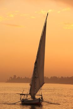 Felucca boat sailing on the Nile river at sunset, Luxor, Egypt